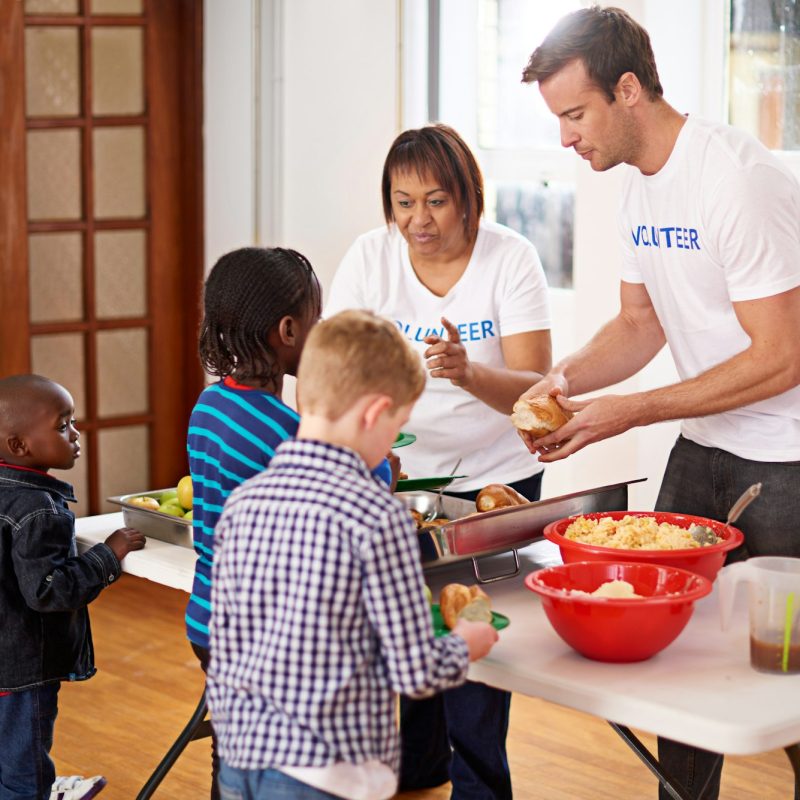 Theres plenty for everyone. Shot of volunteers serving food to a group of little children.